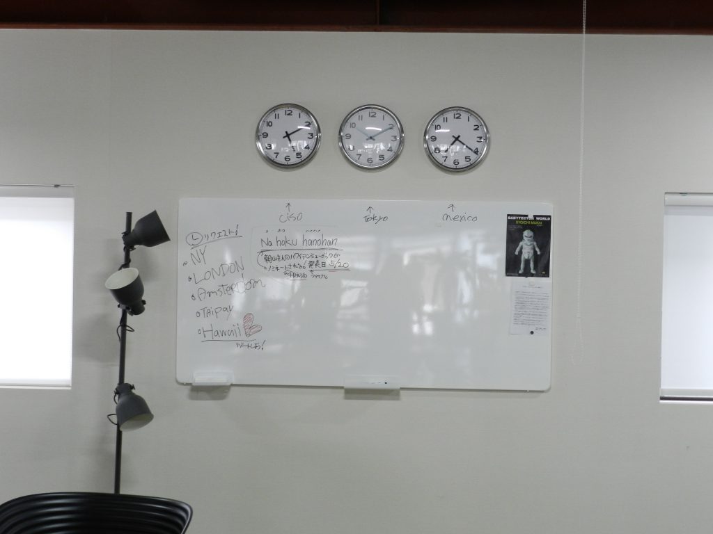 壁にはホワイトボードと世界時計